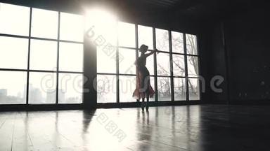 芭蕾舞演员在一扇大窗户的背景下，穿着尖角鞋跳着古典芭蕾。 优雅的芭蕾舞演员